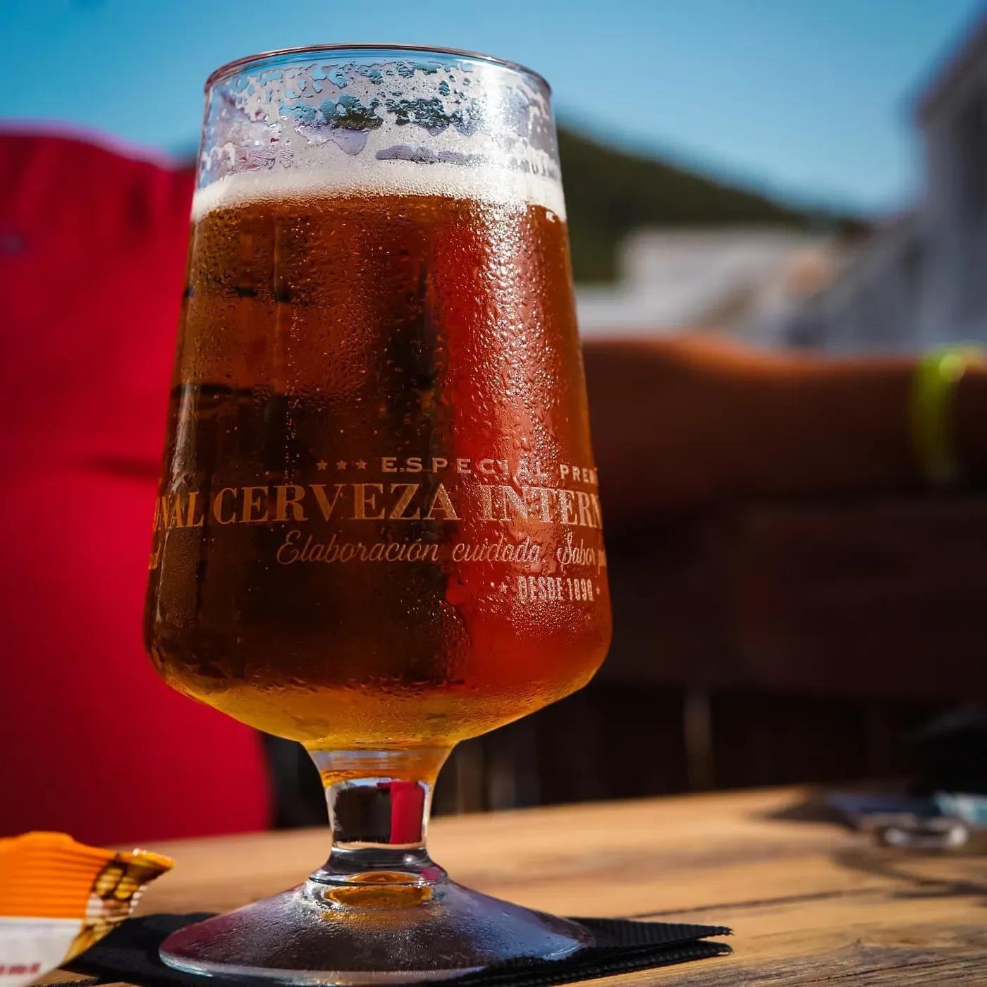 A glass of beer on a table outside, with a red awning behind it